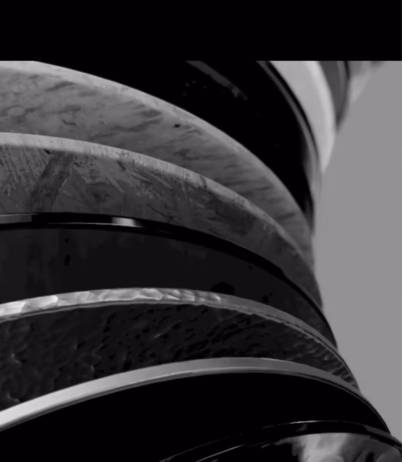 Close-up of stacked metal rings with varied textures and finishes in grayscale.