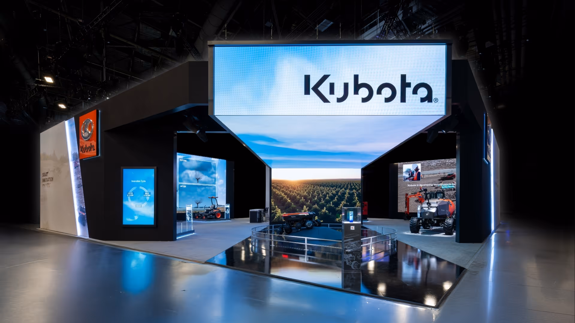 Kubota exhibition booth with machinery displays and large screens showing farm and innovation images.