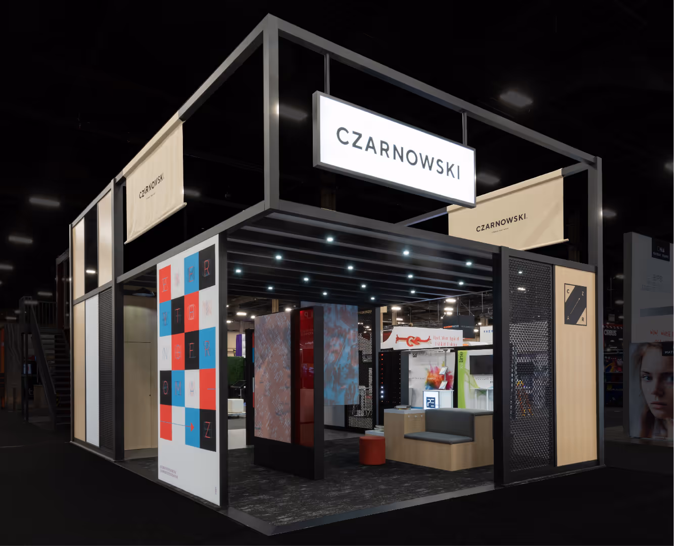 Modern exhibition booth with black frame, seating area, and illuminated CZARNOWSKI signs.