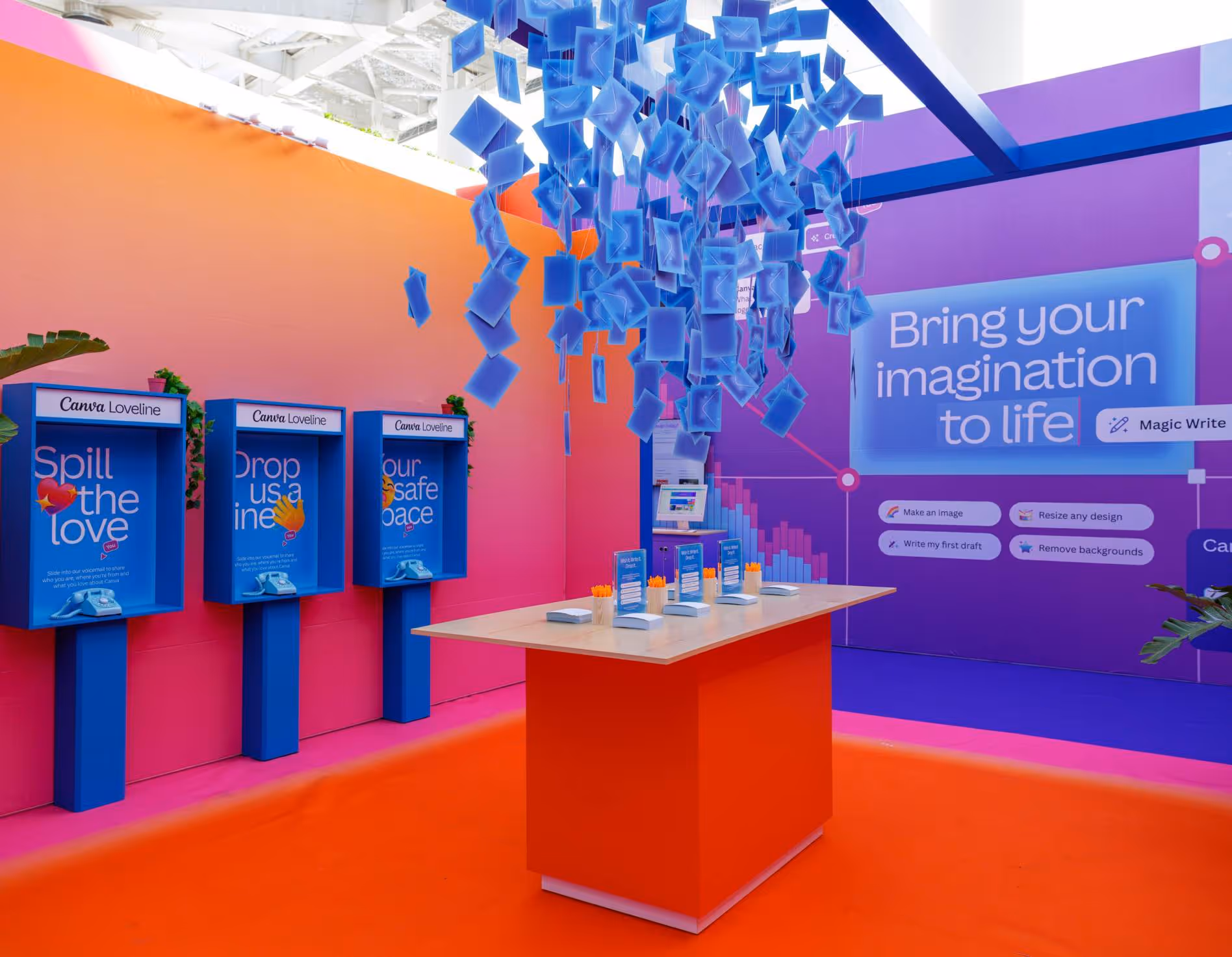 Colorful interactive Canva Loveline booth with phones, a table, and blue hanging paper squares.
