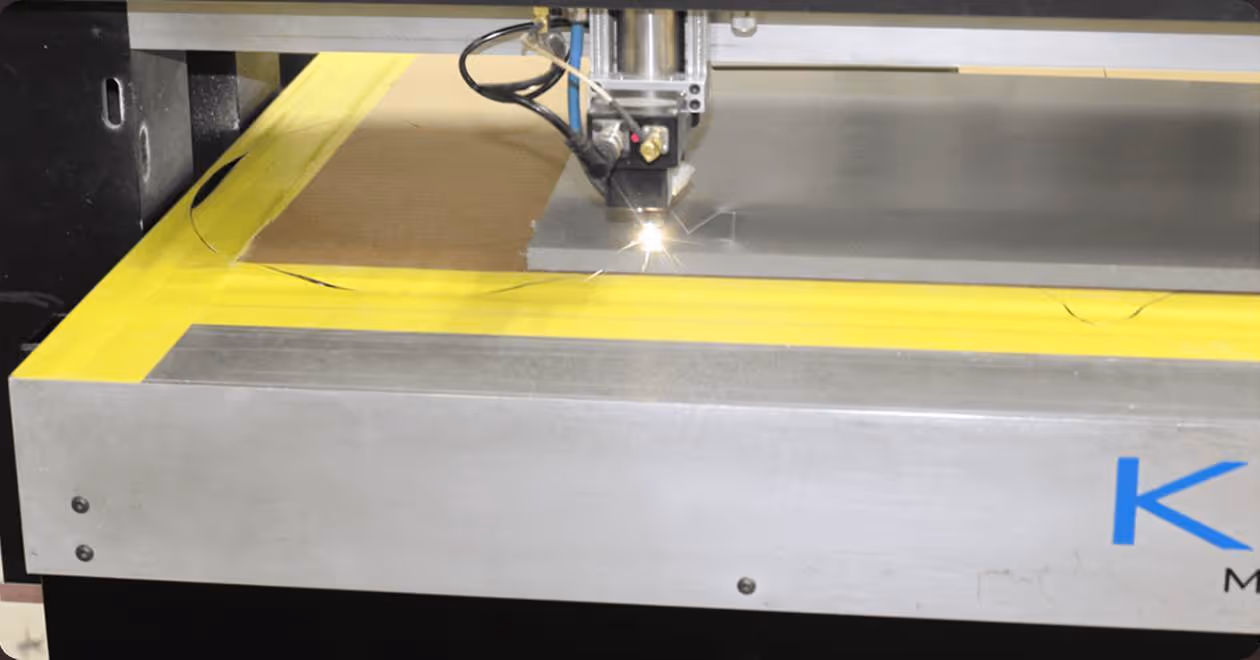 Close-up of a laser cutting machine engraving a metal sheet with sparks flying.