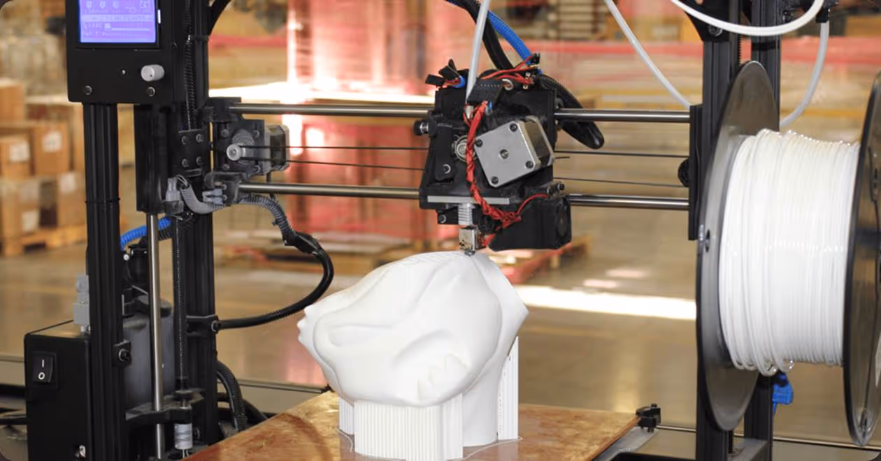 3D printer creating a detailed white sculpture of a face in a workshop setting.