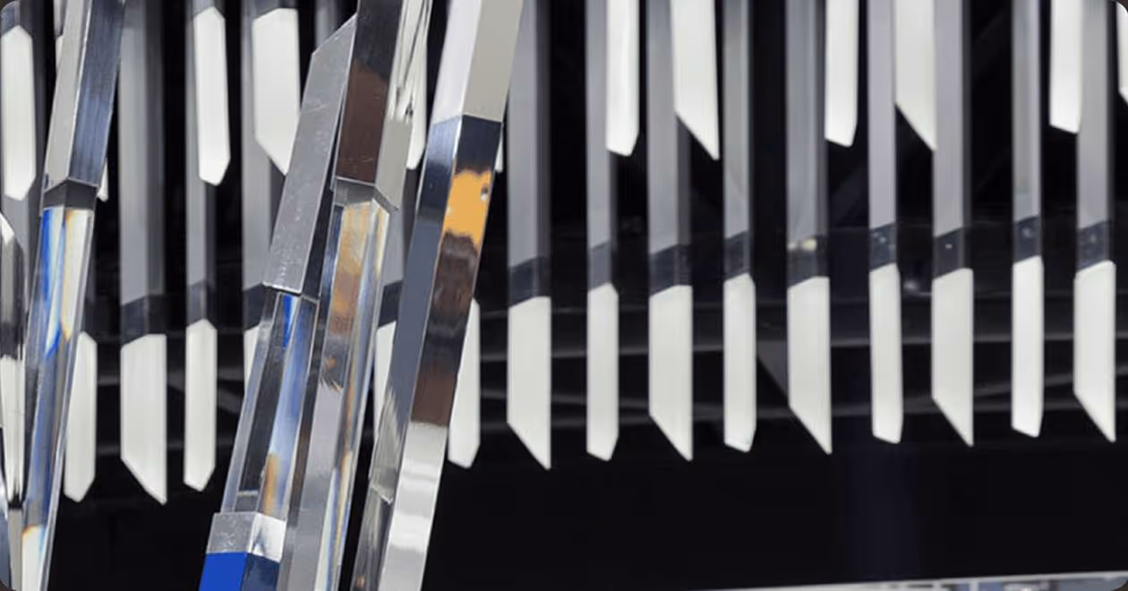 Close-up of shiny, reflective metal prism shapes arranged vertically with sharp edges.