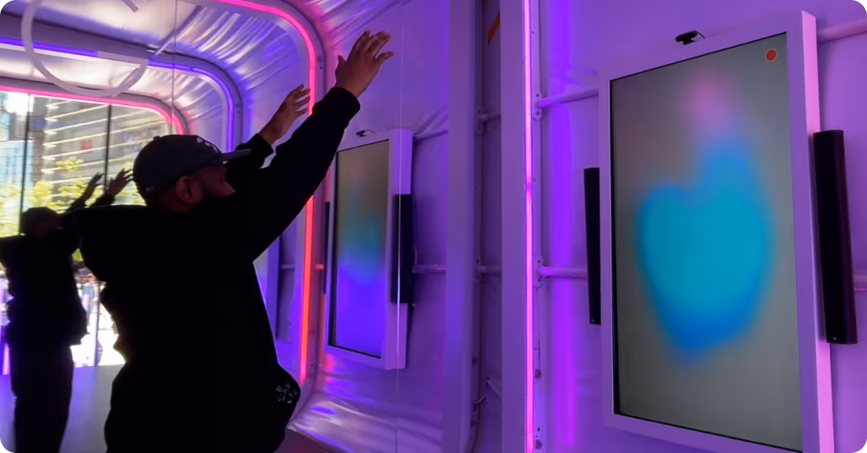Man raising hands interacting with a touchscreen display in a purple-lit modern room.