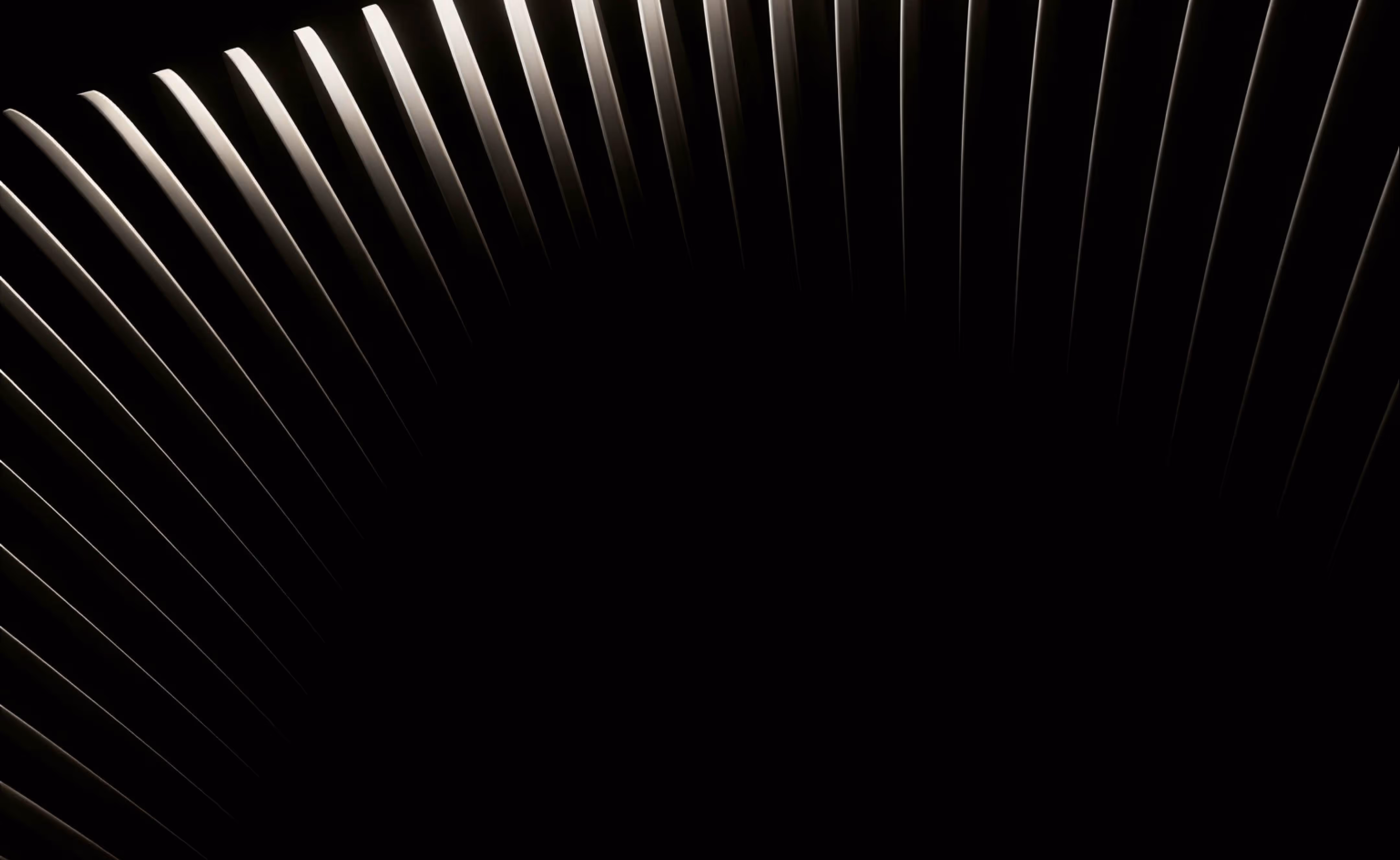Close-up of curved vertical metal slats with light highlighting edges against black background.