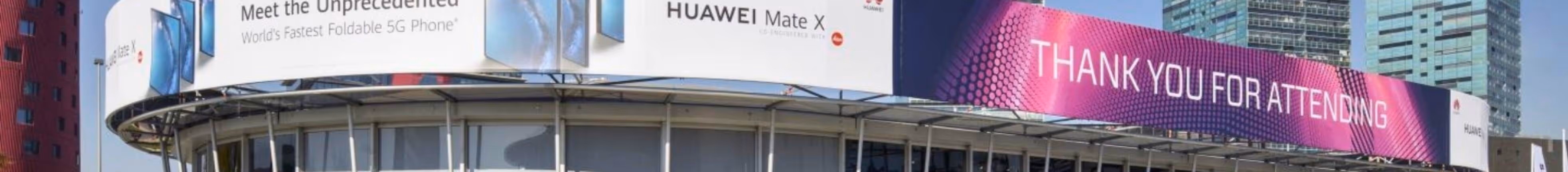 Curved outdoor LED screen on building displaying Huawei Mate X and thank you for attending messages.