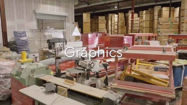Interior of a warehouse with packaging machines, stacks of boxes, and pallets wrapped in plastic.