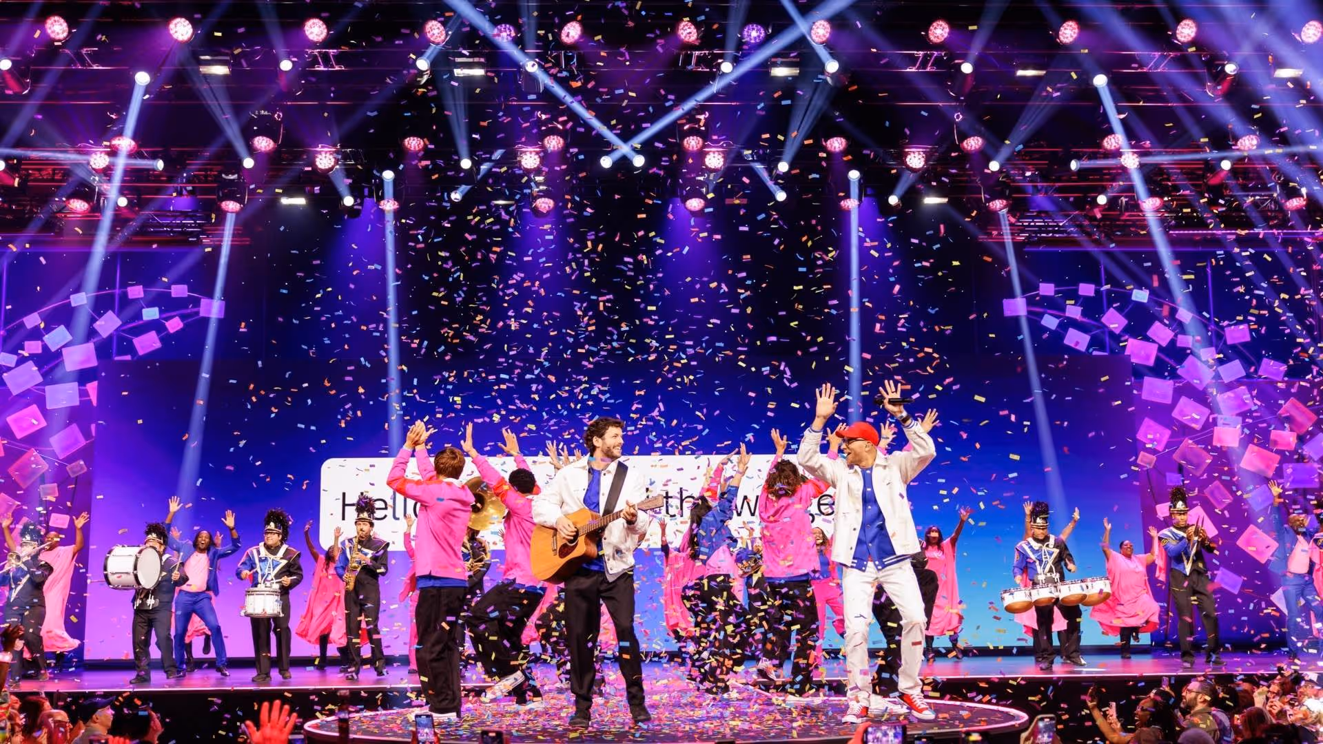 Performers on stage with confetti and lighting effects during a festive music and dance show.