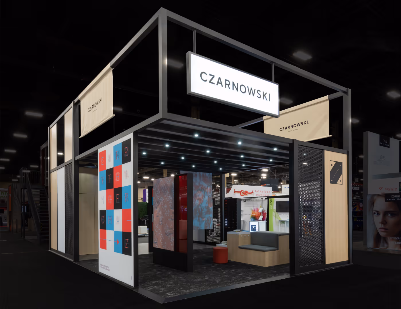 Modern trade show booth for CZARNOWSKI with illuminated sign and seating area inside.