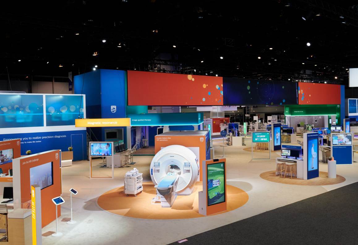 A medical imaging exhibit featuring a white MRI machine with multiple digital displays around it.