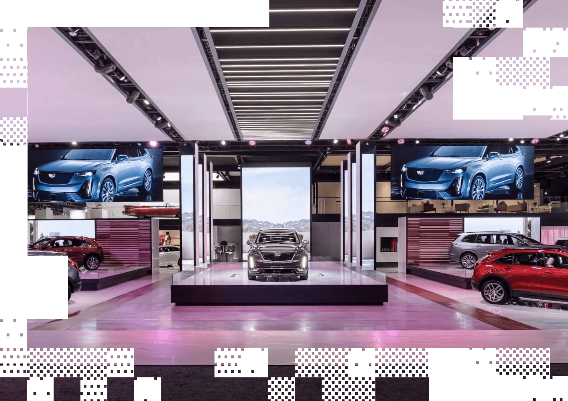 Automobile showroom with a featured Cadillac SUV on a raised platform and screens showing a blue Cadillac.