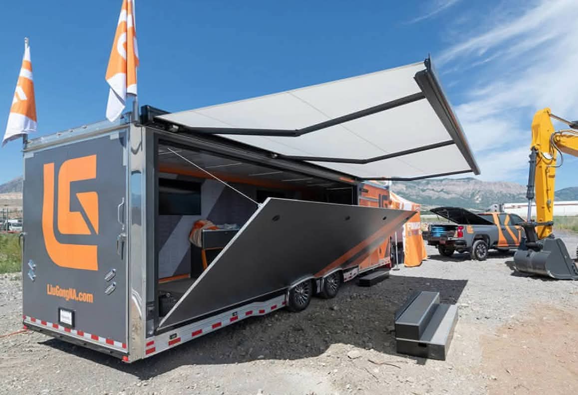 A LuDoNg mobile trailer with open side panels and an extended canopy set on a gravel lot.