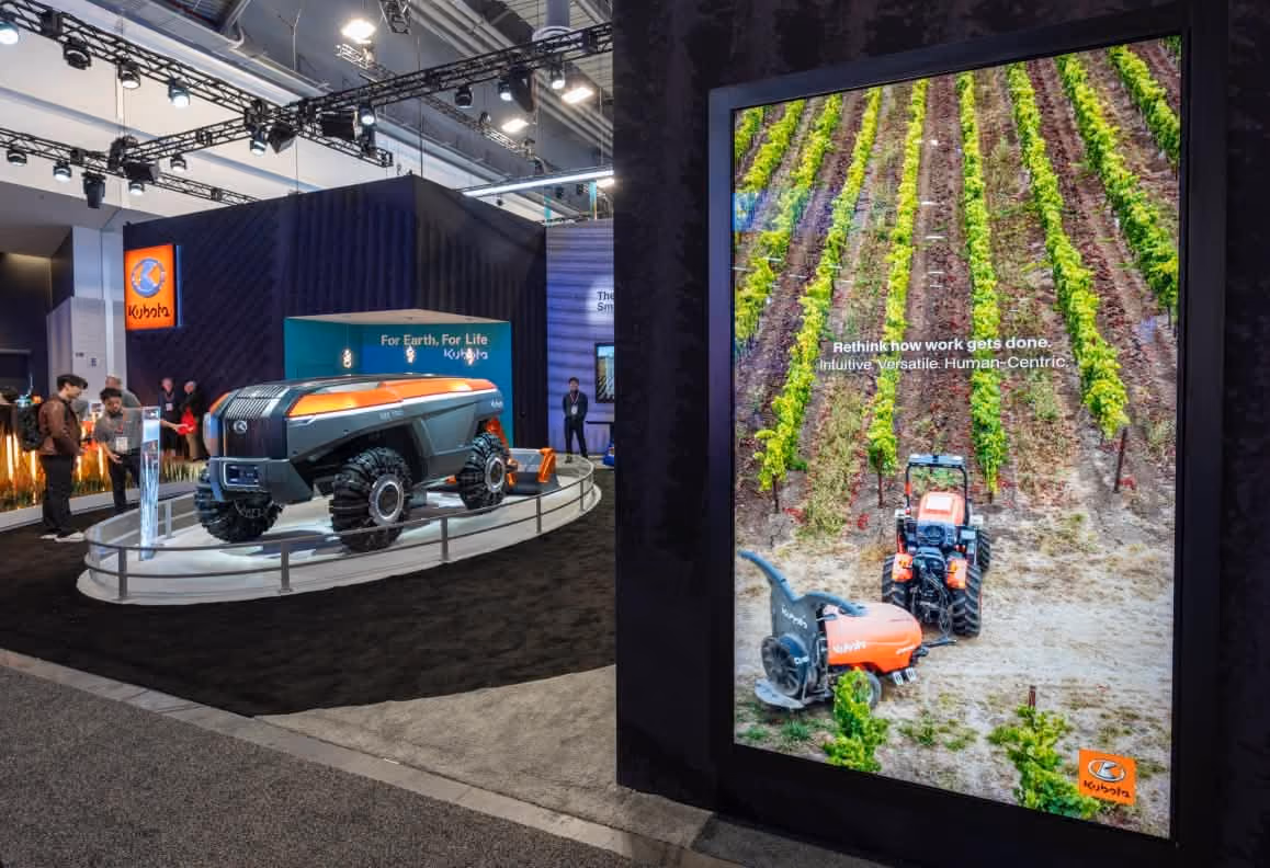Kubota futuristic autonomous vehicle exhibit at a trade show with a digital farm equipment display.