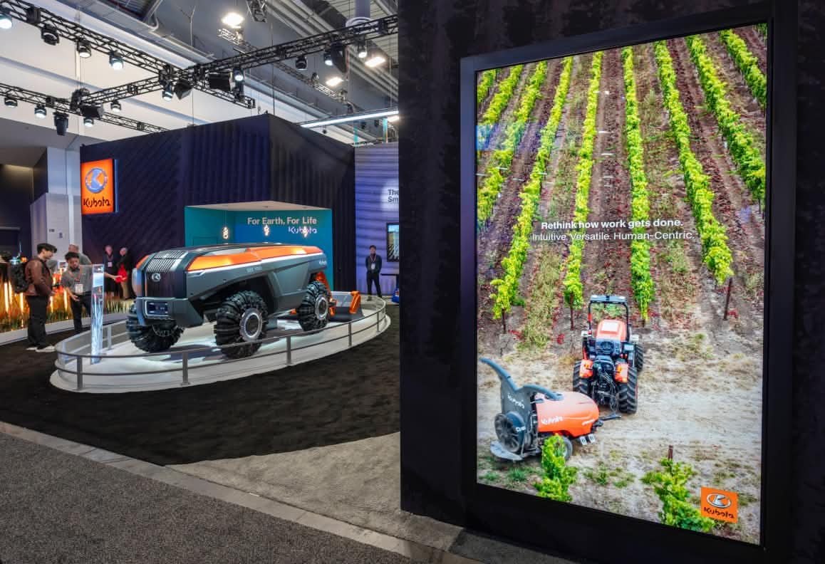 Kubota futuristic autonomous vehicle exhibit at a trade show with a digital farm equipment display.