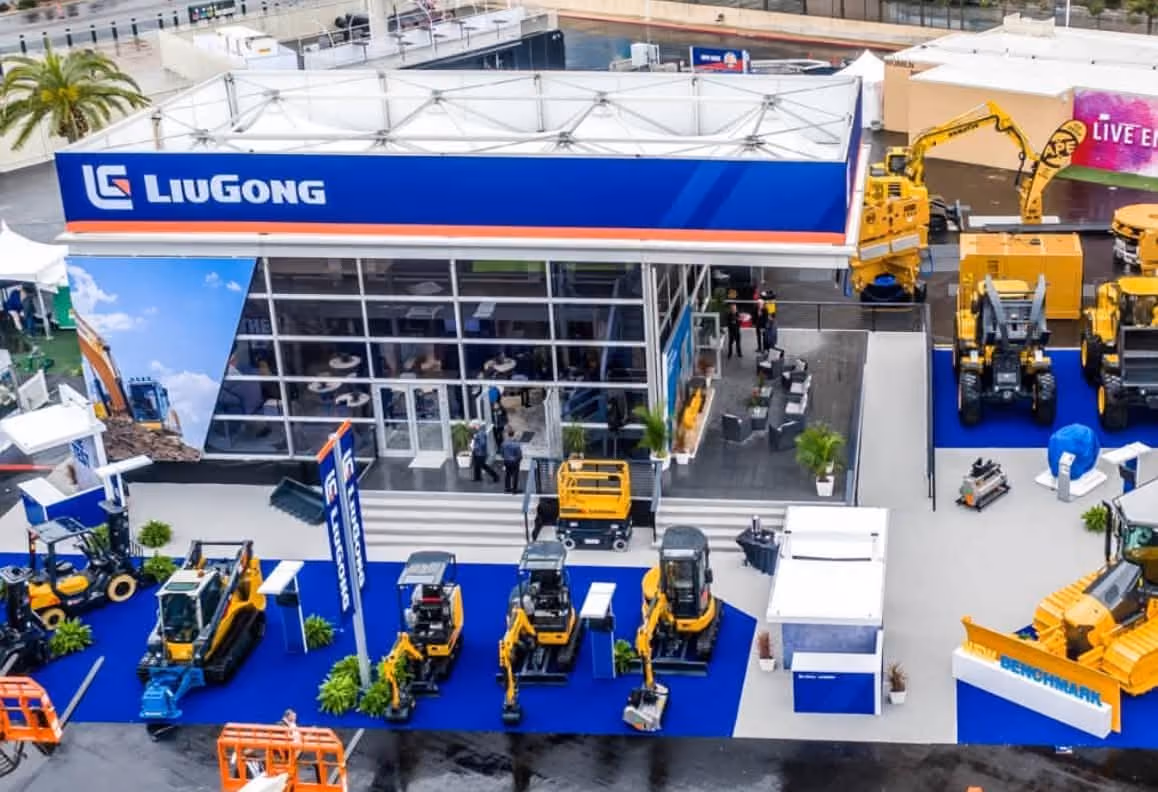 LiuGong trade show booth with yellow construction vehicles displayed on blue carpet outside.