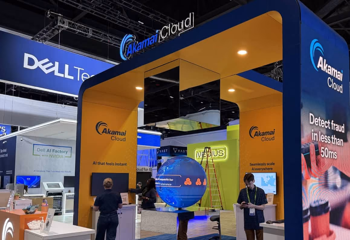 Akamai Cloud trade show booth with digital globe display and slogans about AI and fraud detection.