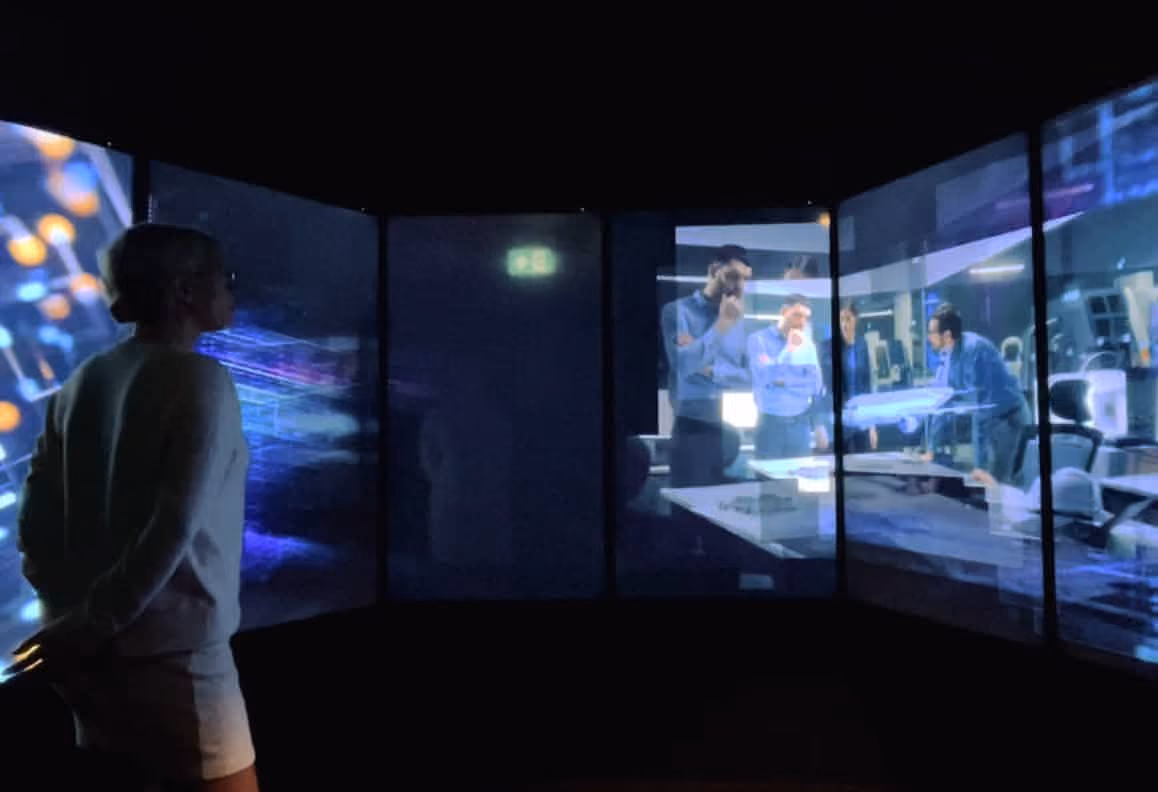 Person watching a multi-panel digital display showing business professionals discussing around a table.