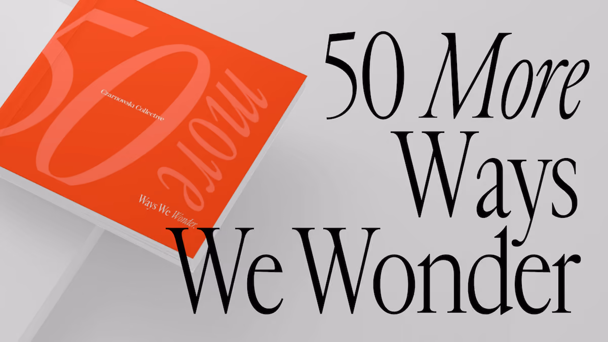 Red book titled '50 More Ways We Wonder' by Czarnowski Collective on a light surface.