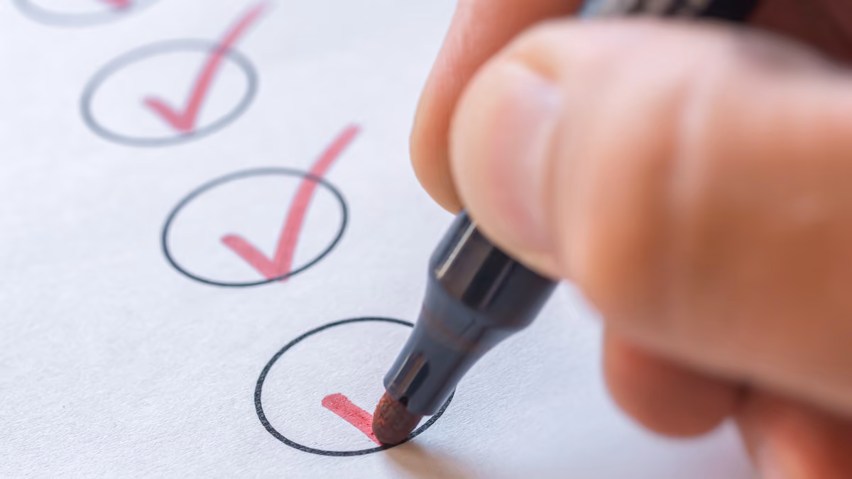 Hand marking red checkmarks inside black circles on white paper with marker.