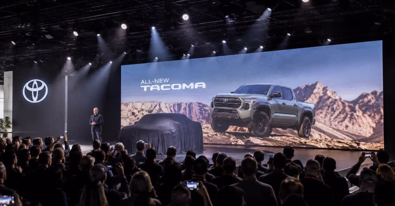 Audience watching a Toyota presentation unveiling the all-new Tacoma pickup truck on stage.