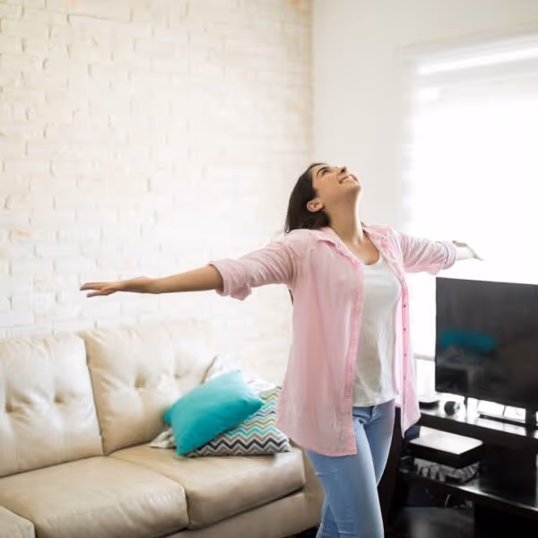 A woman with her arms spread in her living room.