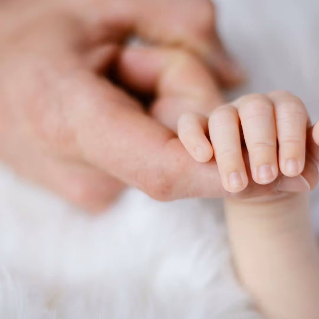 a mother holding an infant's hand with one finger