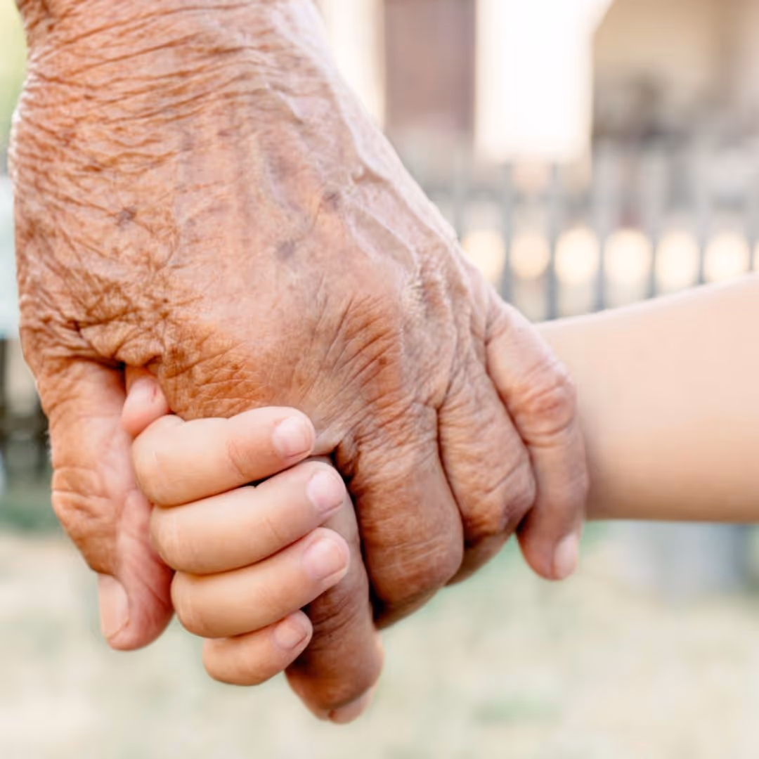 an older, wrinkled hand holding a child's hand