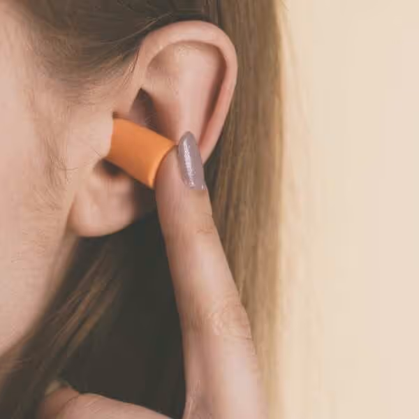 Autistic child wearing ear plugs for sensory overload prevention.
