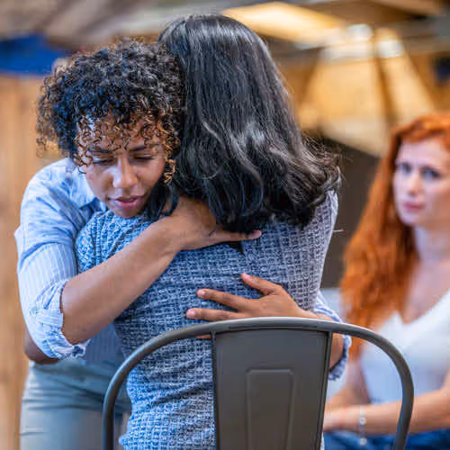 two adults hugging in support group