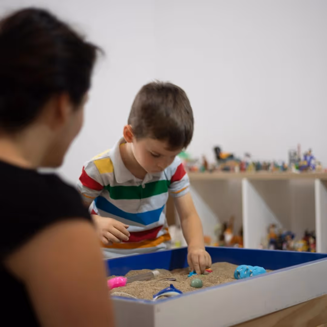kid playing in sandbox in therapy