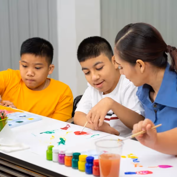 a group of children painting with adult supervision