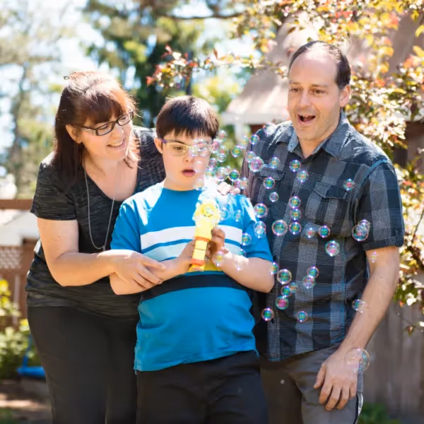 a child and parents playing with bubbles outside