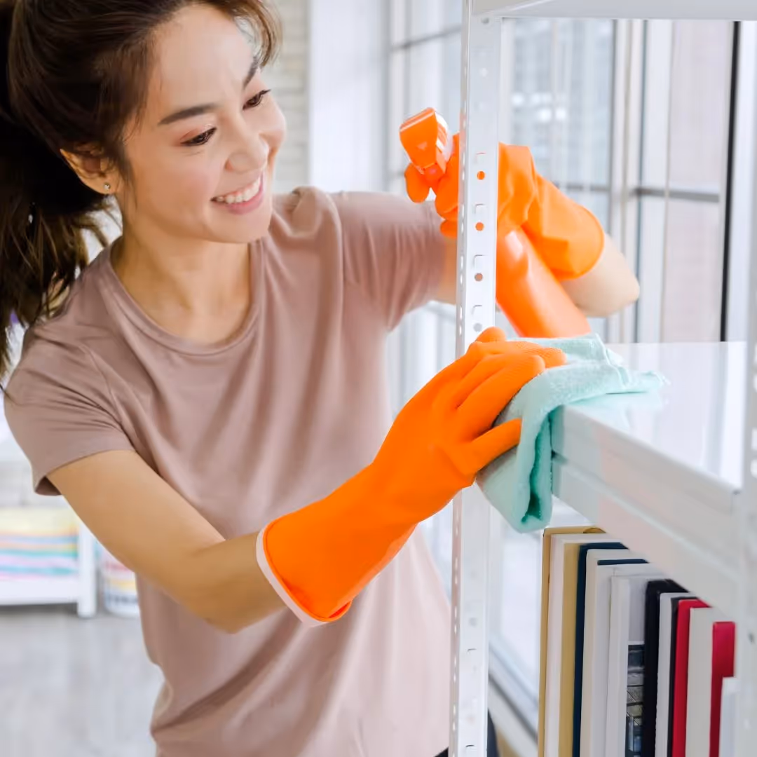 Person wearing cleaning gloves wiping down a shelf
