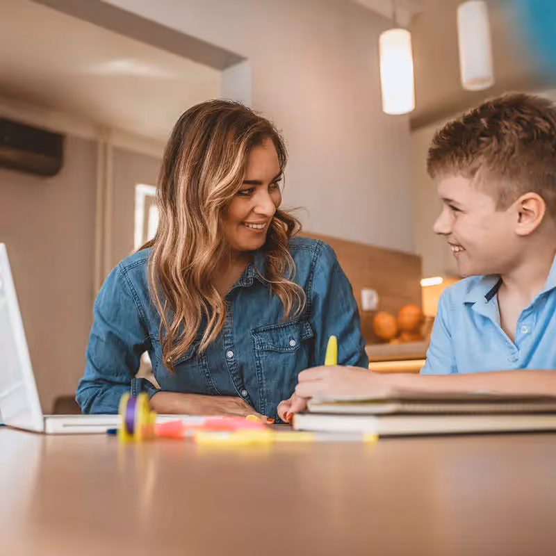 A person working with a child using a laptop and papers