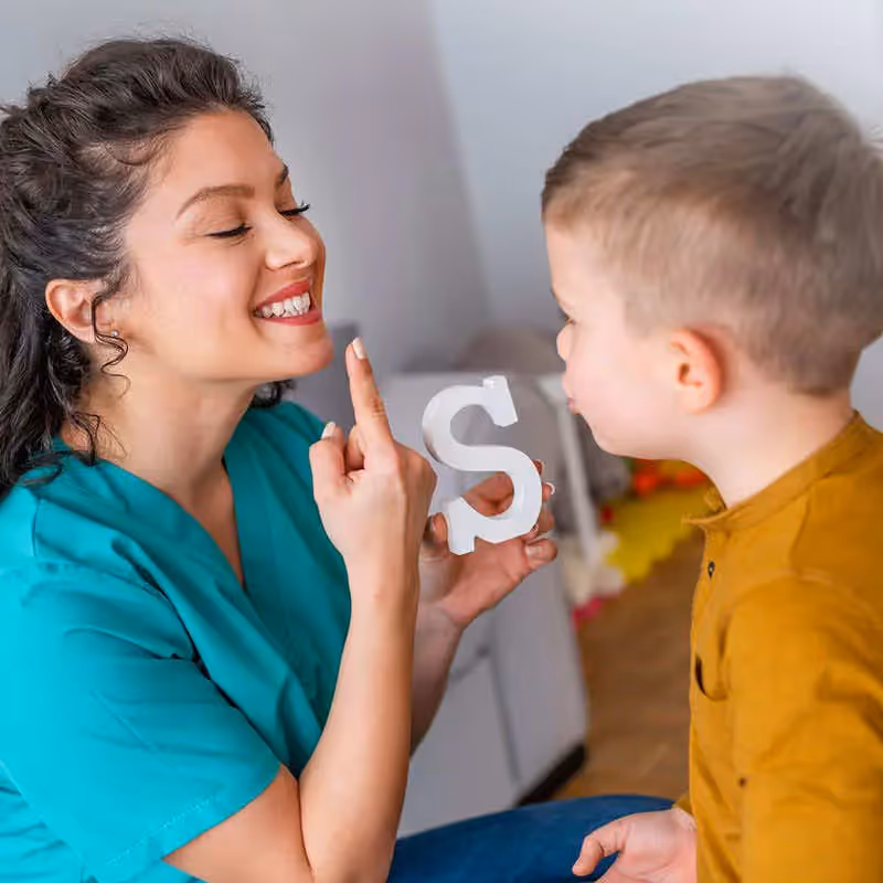 Person demonstrating to a child how to make the sound of the letter "S"