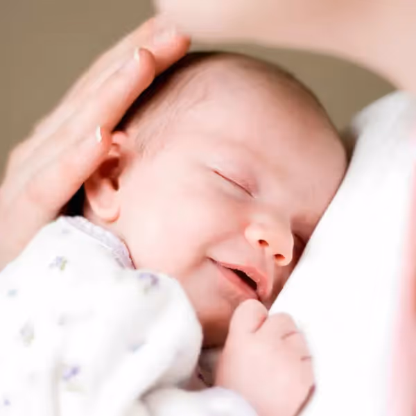 a newborn smiling against a woman's chest
