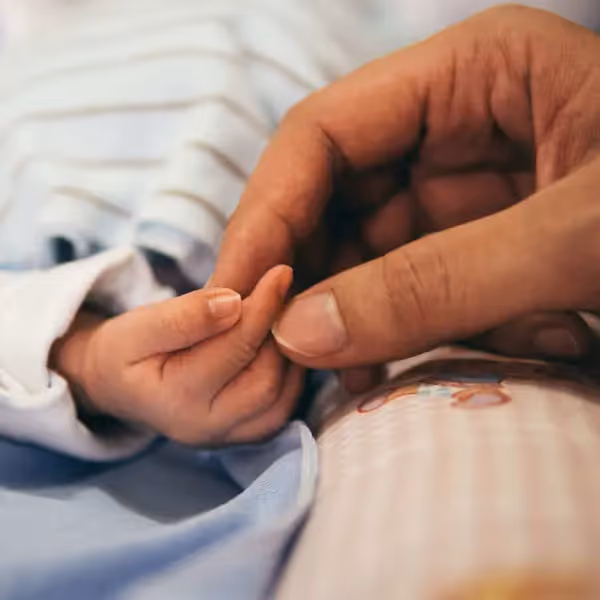 a mother and newborn holding hands