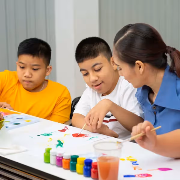 a teacher doing painting crafts with autistic students