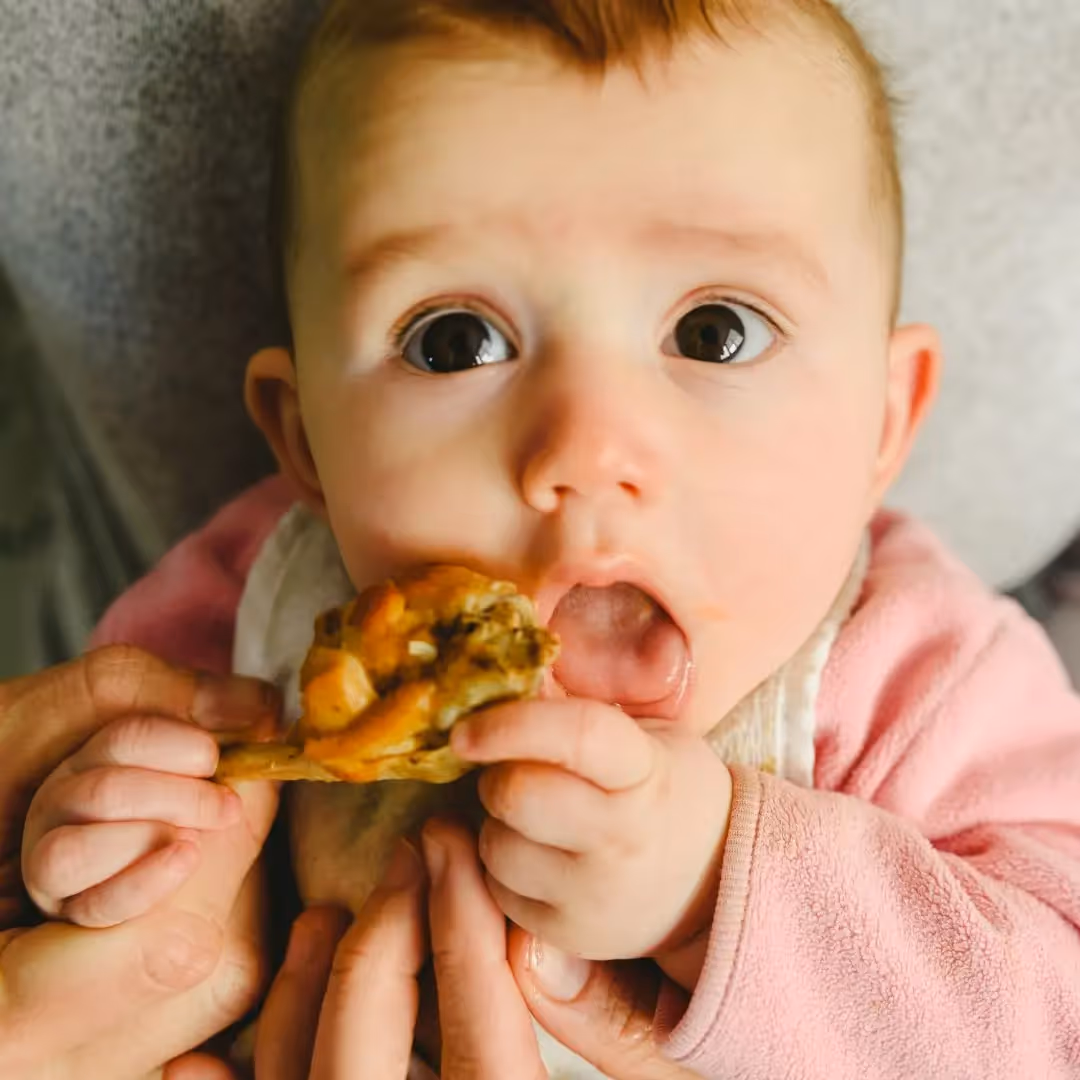 infant eating a bite of food
