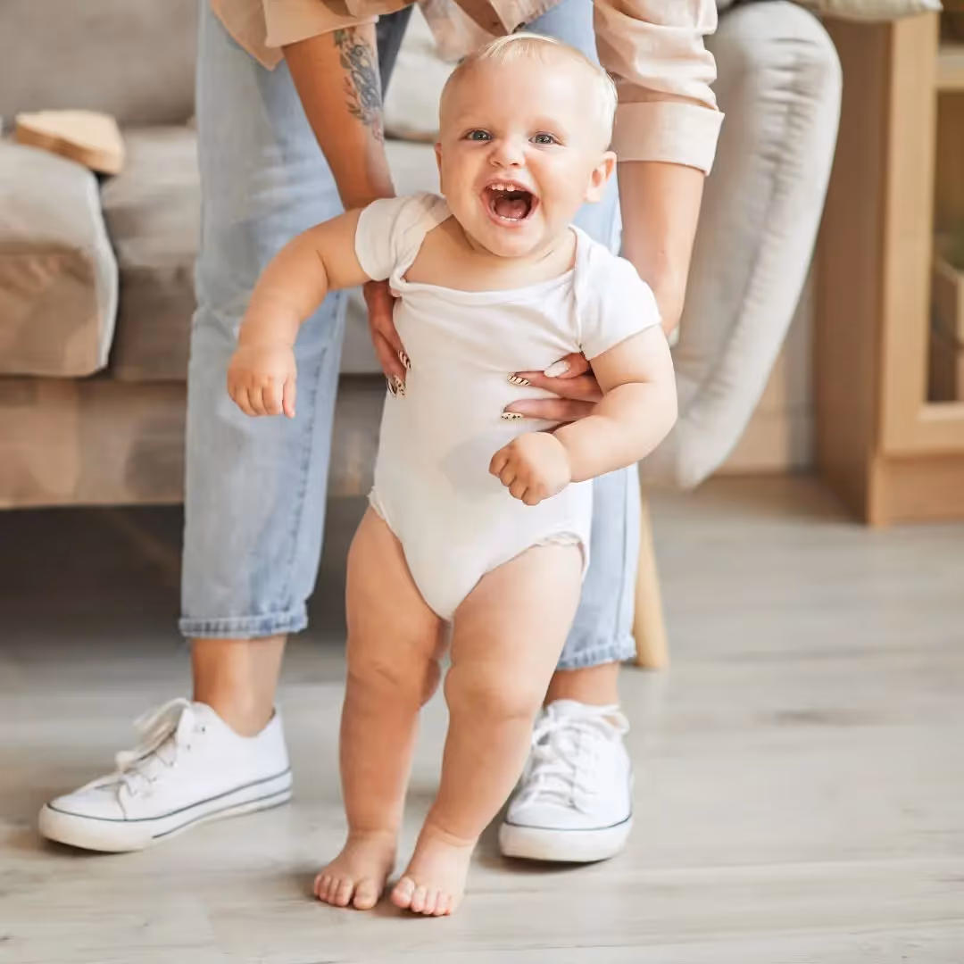 Mom holding her baby while they try to walk. 
