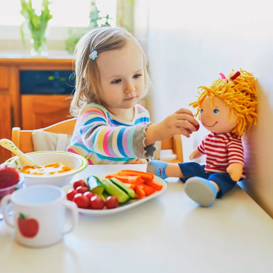 Young girl feeding a doll.