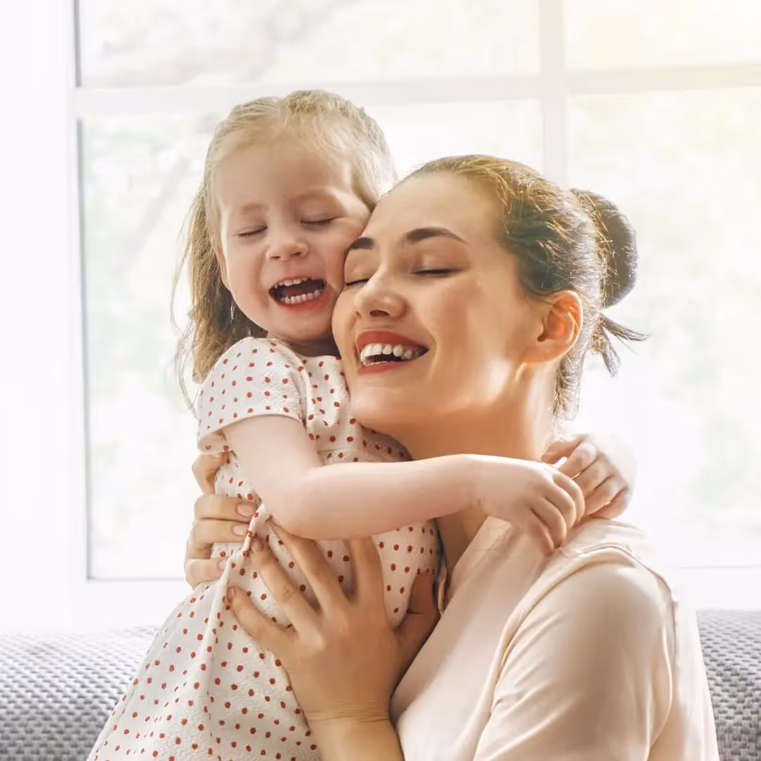 Young girl cuddled up to a woman, hugging her.