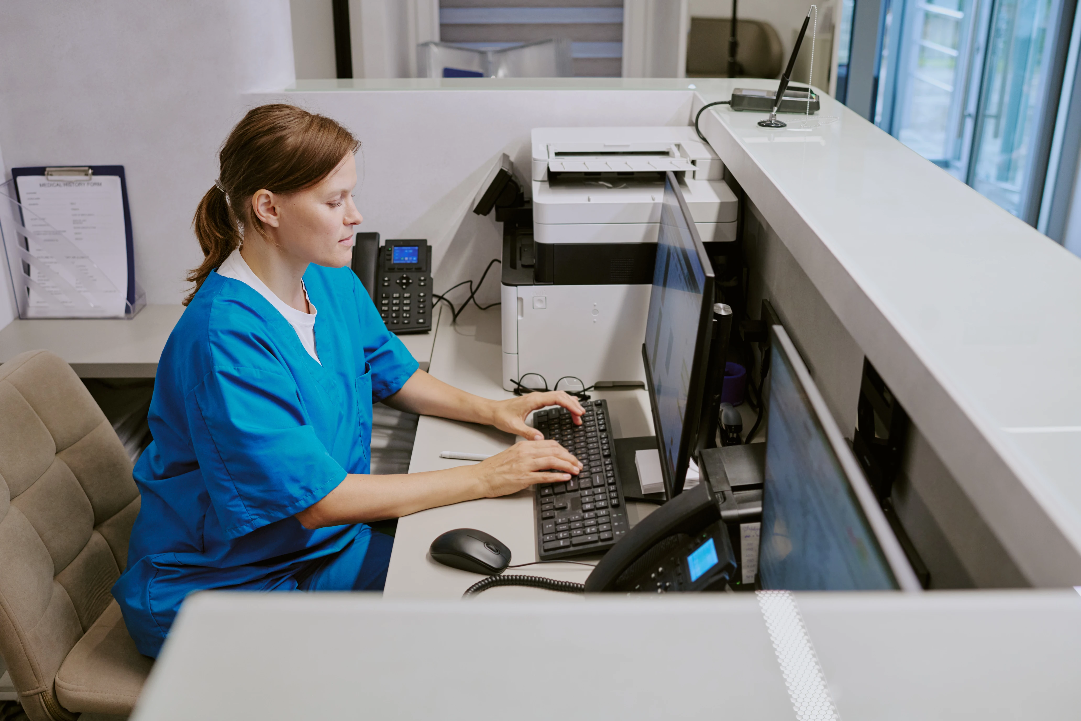 Healthcare administrator working at computer managing hospital data systems