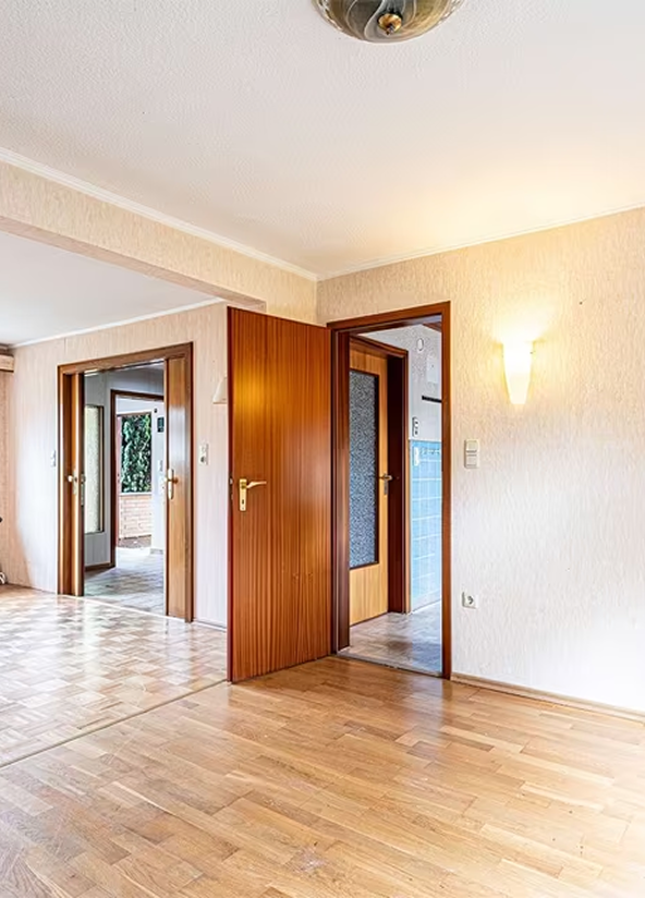 An empty room with wooden floors and doors.