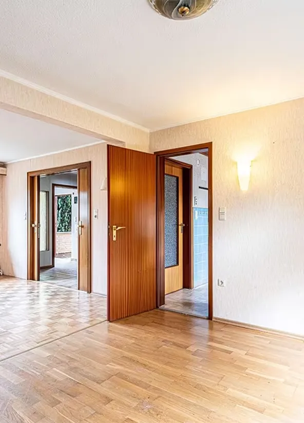An empty room with wooden floors and doors.