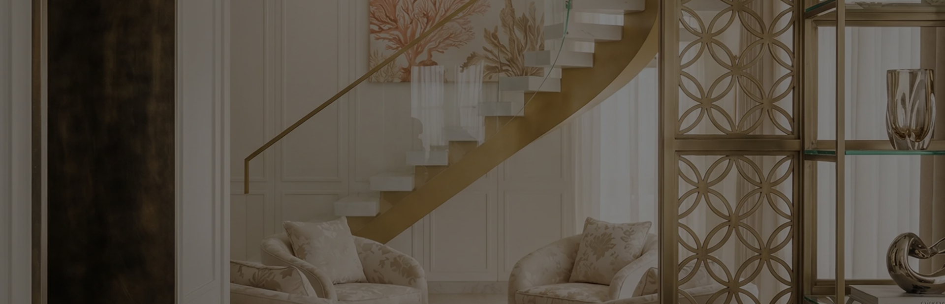 A living room with a stair case and two chairs.