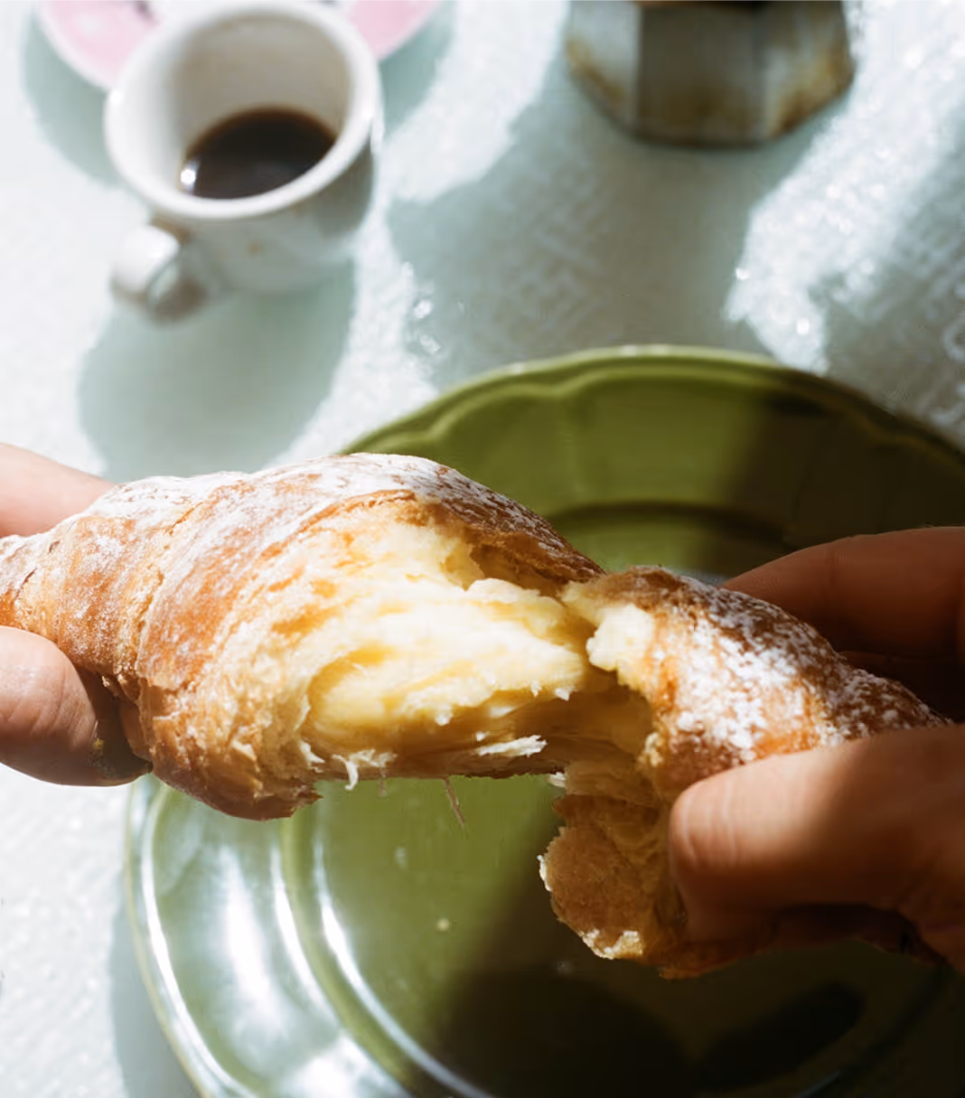 An image of a croissant being teared apart to eat with sunlight basking the table, from Death to Stock by Parole Dure