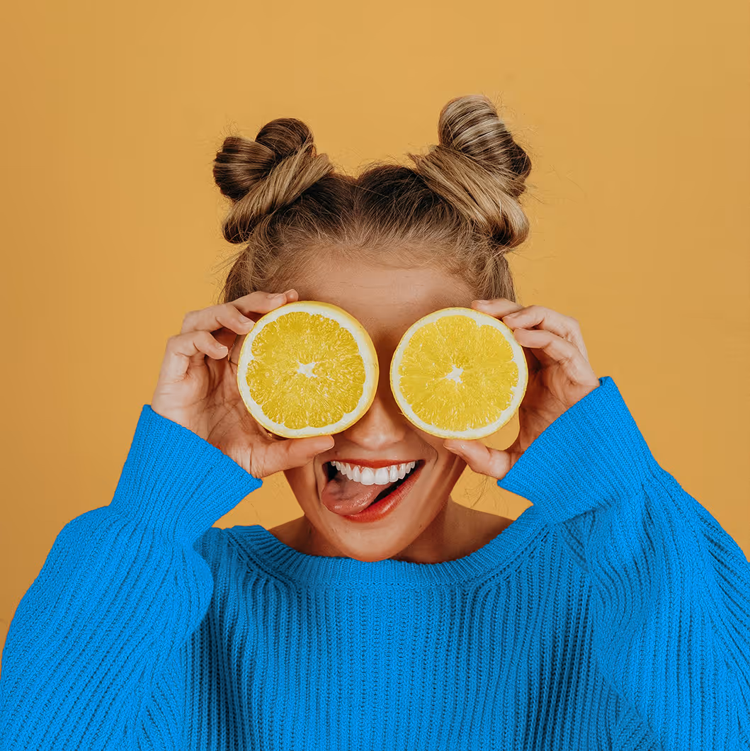 An image of a woman covering her eyes with lemon slices, from Noah Buscher on Unsplash