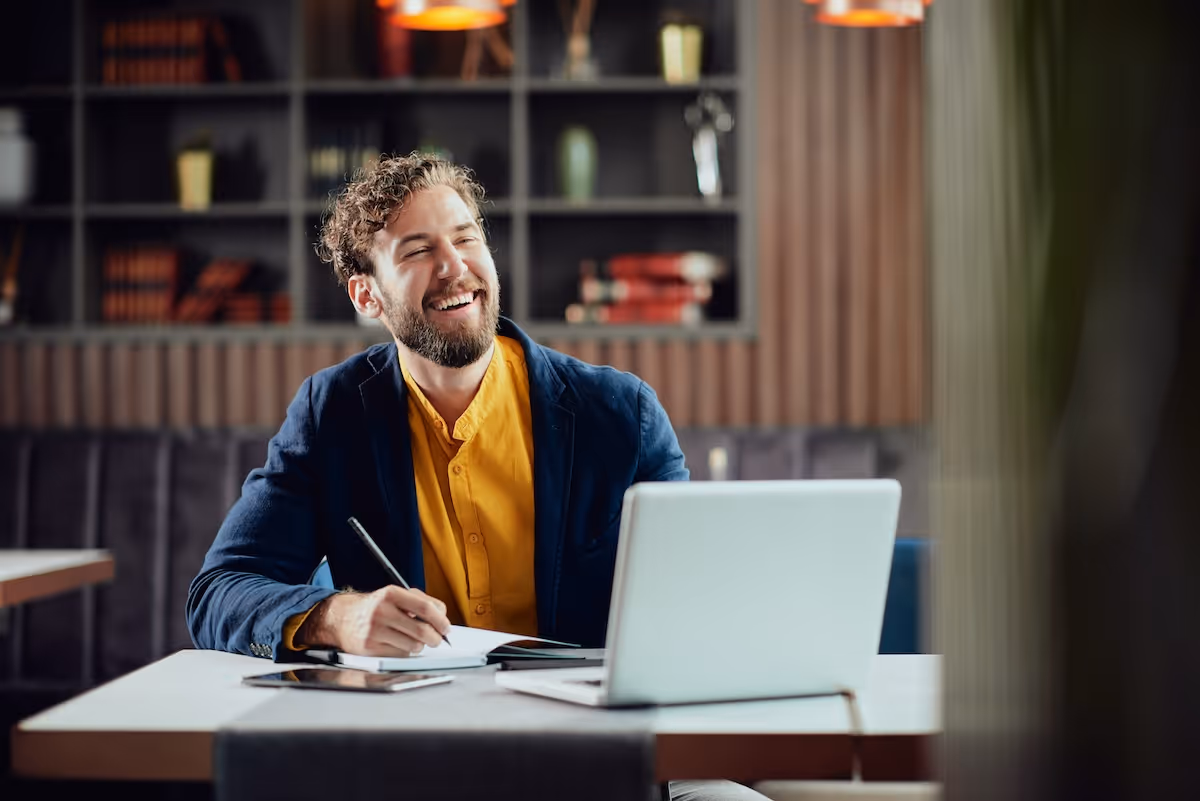 View of a calm river framed by a stone arch bridge with lush green trees reflected in the water.