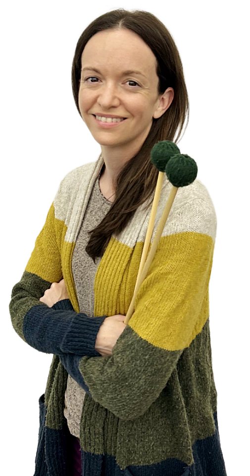 Photograph of Marissa Turney, smiling woman with long brown hair wearing a multicolored cardigan holding green yarn mallets.